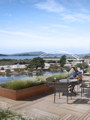 Outdoor seating area on the water with a bridge in the background
